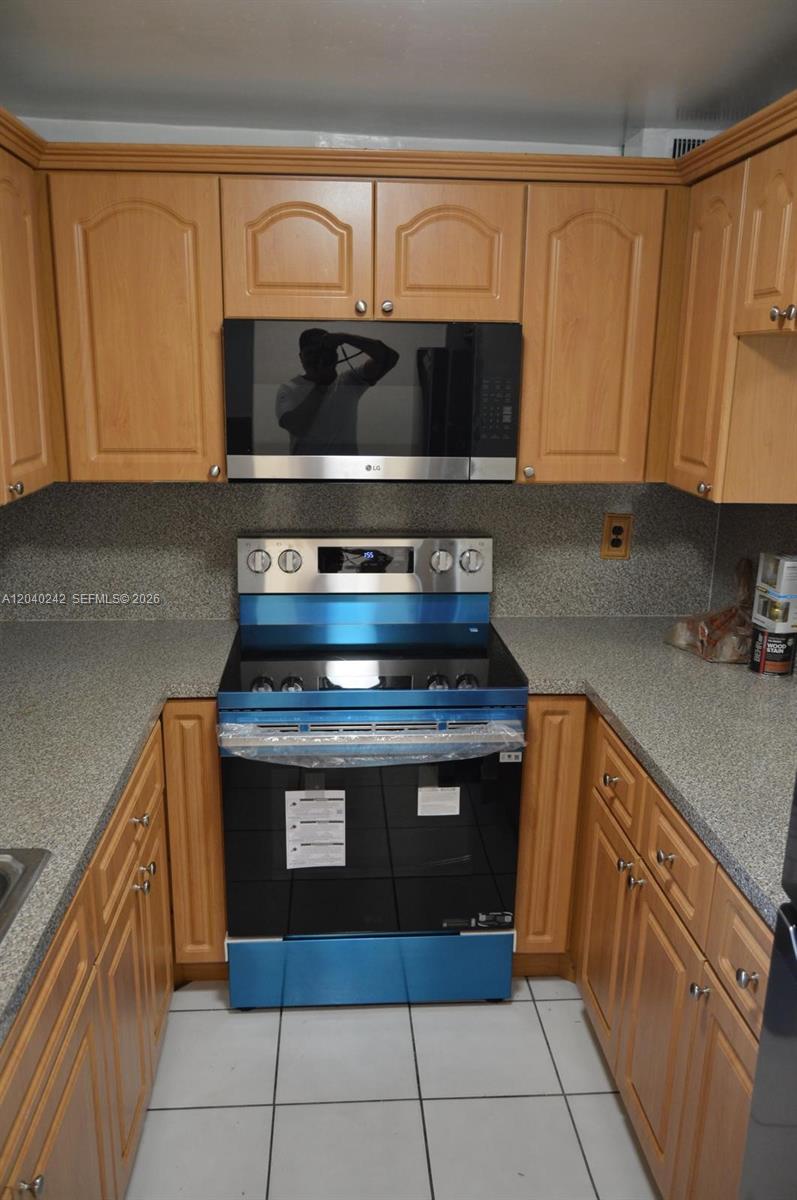 A kitchen features light wood cabinets, a stainless steel stove, and a microwave above — 1910 W 56th St # 3312, Hialeah FL 33012, HIALEAH, FL