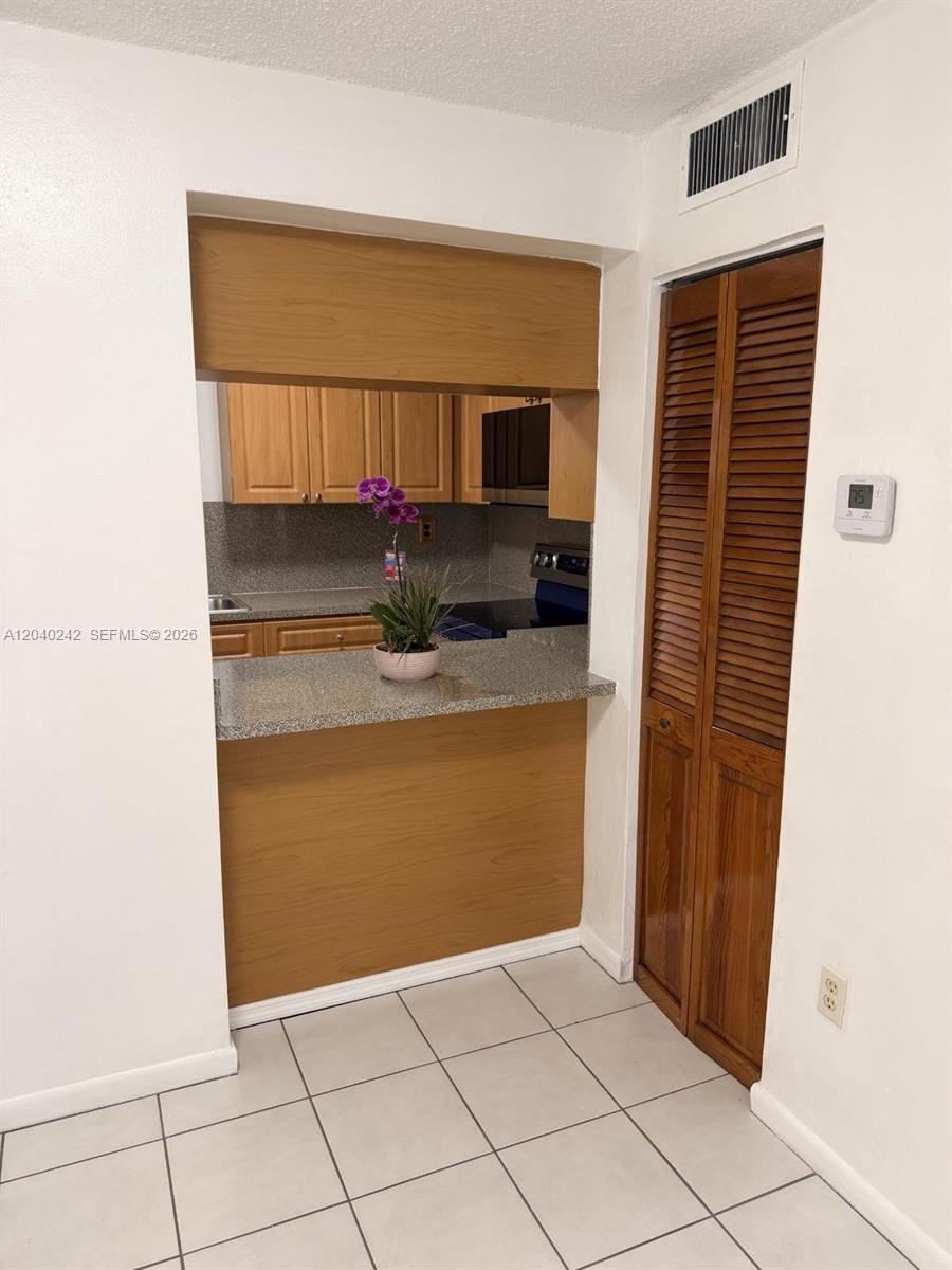 A kitchen with a granite pass-through counter, wooden cabinets, and a louvered closet door — 1910 W 56th St # 3312, Hialeah FL 33012, HIALEAH, FL