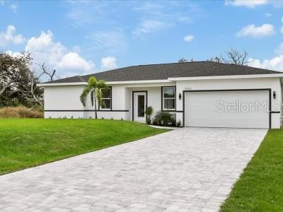 A white single-story house with a dark roof and a paved driveway under a blue sky — 12005 HELICON AVENUE, PORT CHARLOTTE, FL