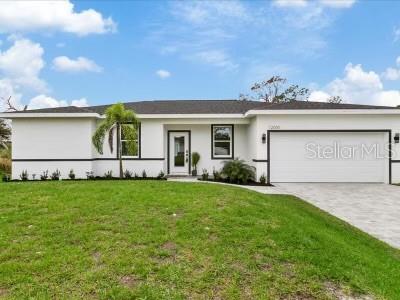 A single-story white house with a dark roof, a two-car garage, and a front lawn — 12005 HELICON AVENUE, PORT CHARLOTTE, FL