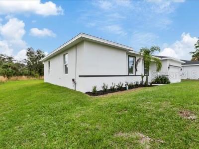 A side view of a white, single-story house with a palm tree and green lawn — 12005 HELICON AVENUE, PORT CHARLOTTE, FL