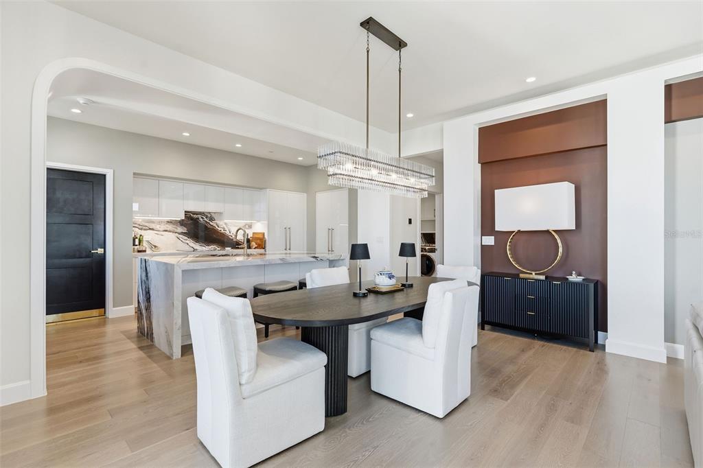 A modern dining area features a dark oval table, white chairs, and a crystal chandelier — 126 4TH AVENUE NE UNIT 1401, ST PETERSBURG, FL