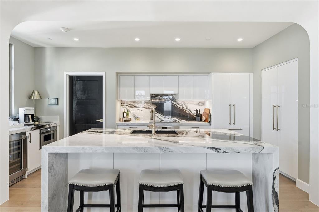 A modern kitchen features a large marble waterfall island, white cabinetry, and dark stone backsplash — 126 4TH AVENUE NE UNIT 1401, ST PETERSBURG, FL