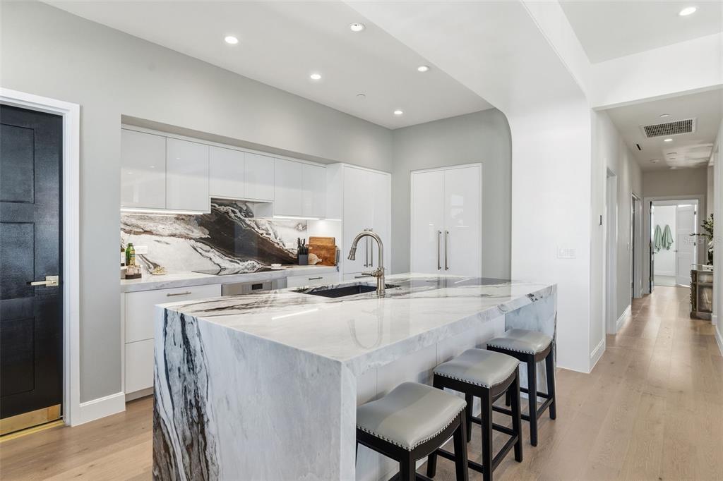 A modern kitchen features a waterfall marble island, white cabinetry, and light wood flooring — 126 4TH AVENUE NE UNIT 1401, ST PETERSBURG, FL