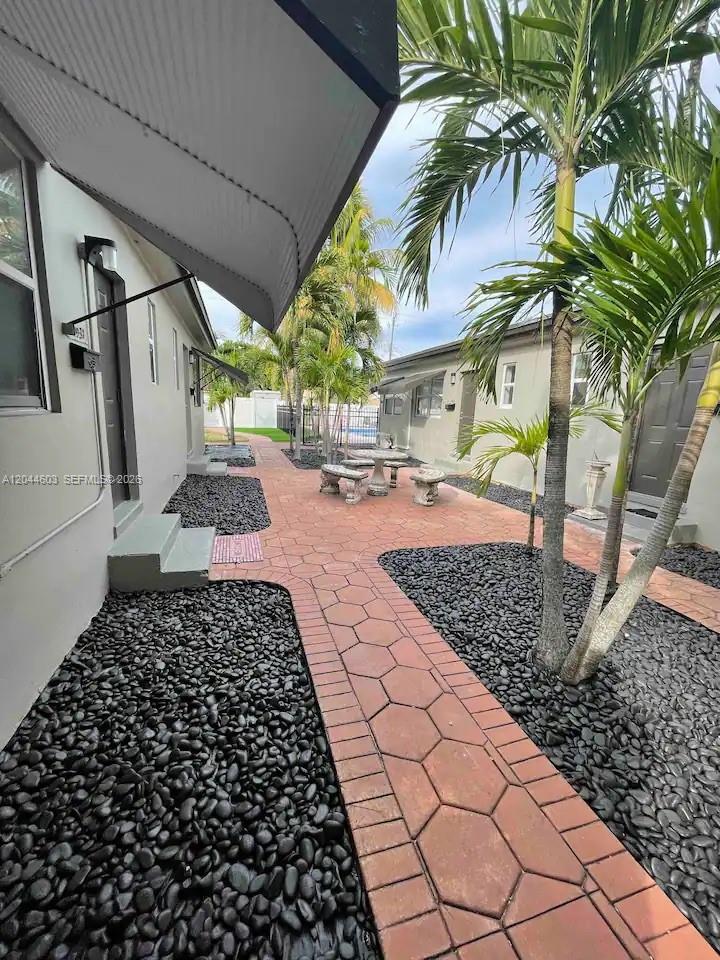 A paved courtyard features black stone landscaping, palm trees, and a small outdoor seating area — 1925 Dewey St, Hollywood FL 33020, HOLLYWOOD, FL