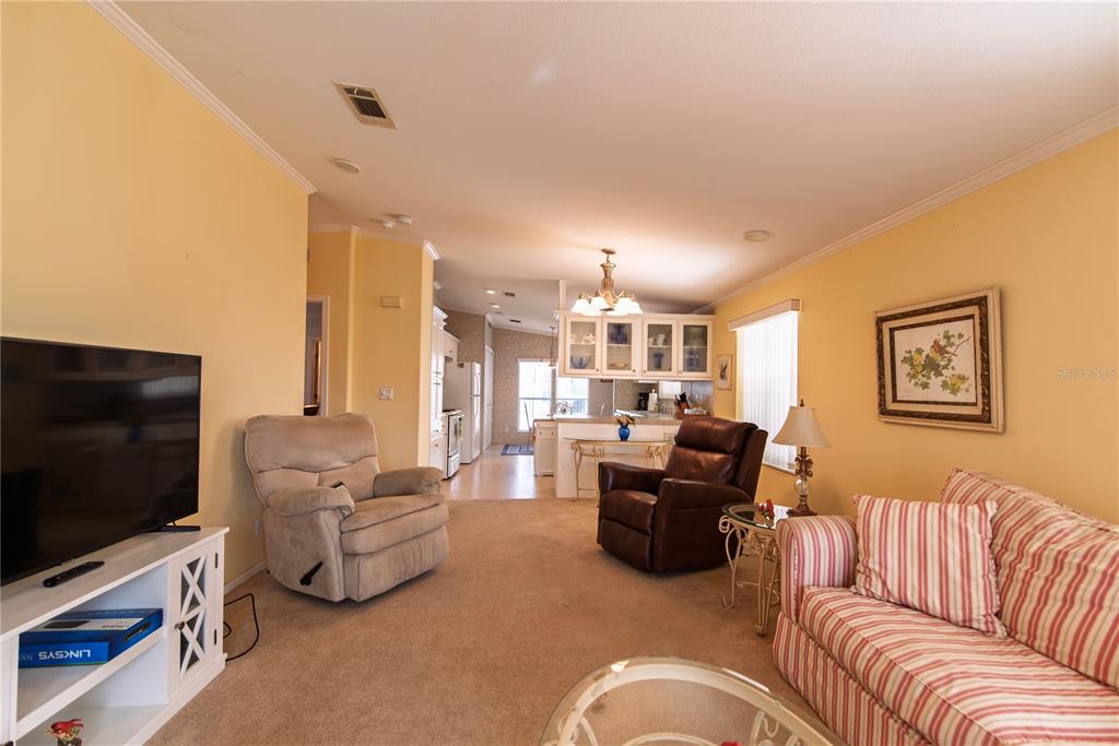 A living room with beige carpet, a striped sofa, two recliners, and a television — 33 AMSTERDAM AVENUE, PUNTA GORDA, FL