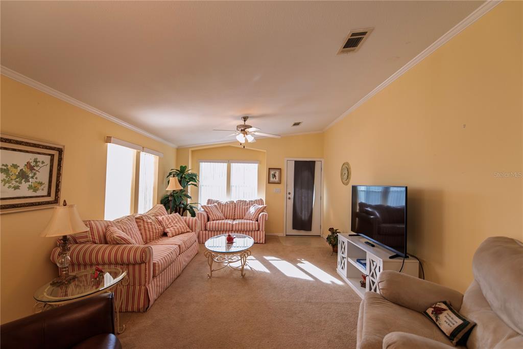 A living room features yellow walls, striped furniture, a ceiling fan, and a television console — 33 AMSTERDAM AVENUE, PUNTA GORDA, FL