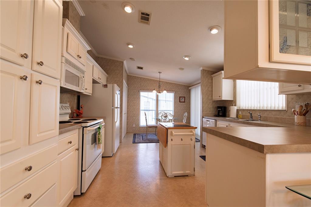 A kitchen features white cabinets, a central island, and an adjacent dining area with a window — 33 AMSTERDAM AVENUE, PUNTA GORDA, FL