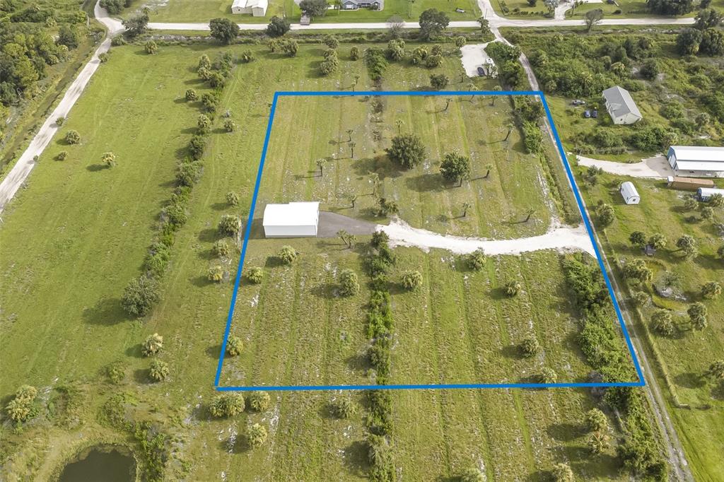 An aerial view shows a rectangular property lot with a white building and driveway — 7057 AUSTRIAN BOULEVARD, PUNTA GORDA, FL