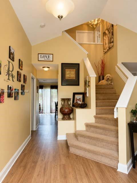 An entryway features wood-look flooring, a carpeted staircase with a dog, and yellow walls — 4351 Leicester Ct, West Palm Beach FL 33409, WEST PALM BEACH, FL