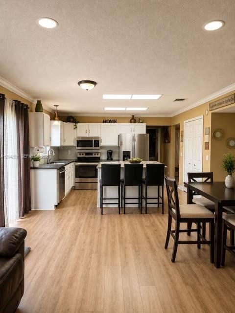 A kitchen with white cabinets, stainless steel appliances, and a breakfast bar with three chairs — 4351 Leicester Ct, West Palm Beach FL 33409, WEST PALM BEACH, FL