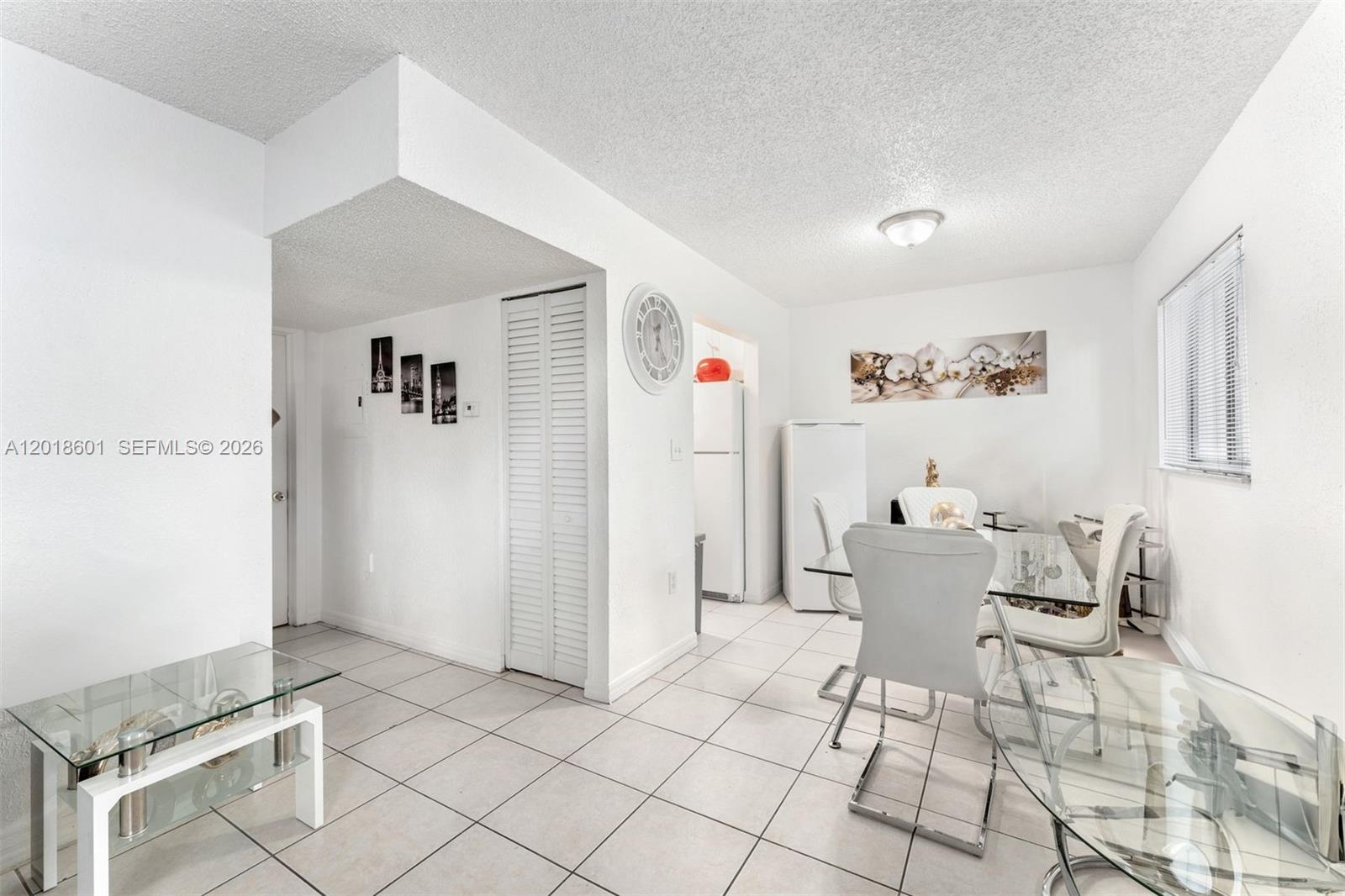 A dining area features white tile floors, a glass table, and white chairs — 5706 W 26th Ave # 5706, Hialeah FL 33016, HIALEAH, FL