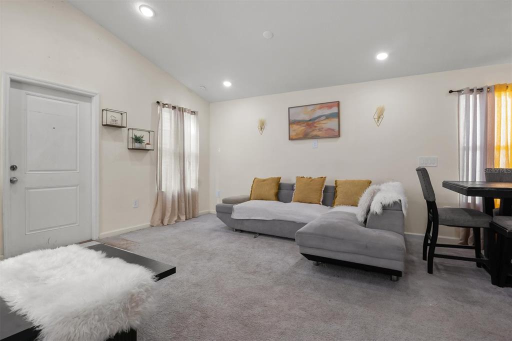 A living room features a grey sectional sofa, carpeted floors, and a dining area — 1665 TEAGAN LANE, WINTER HAVEN, FL