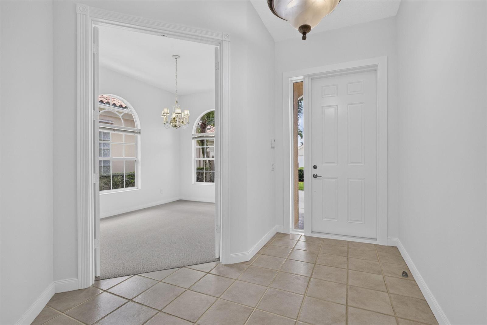 A tiled entryway leads to a carpeted room with arched windows and a chandelier — 2625 Kittbuck Way, West Palm Beach FL 33411, WEST PALM BEACH, FL