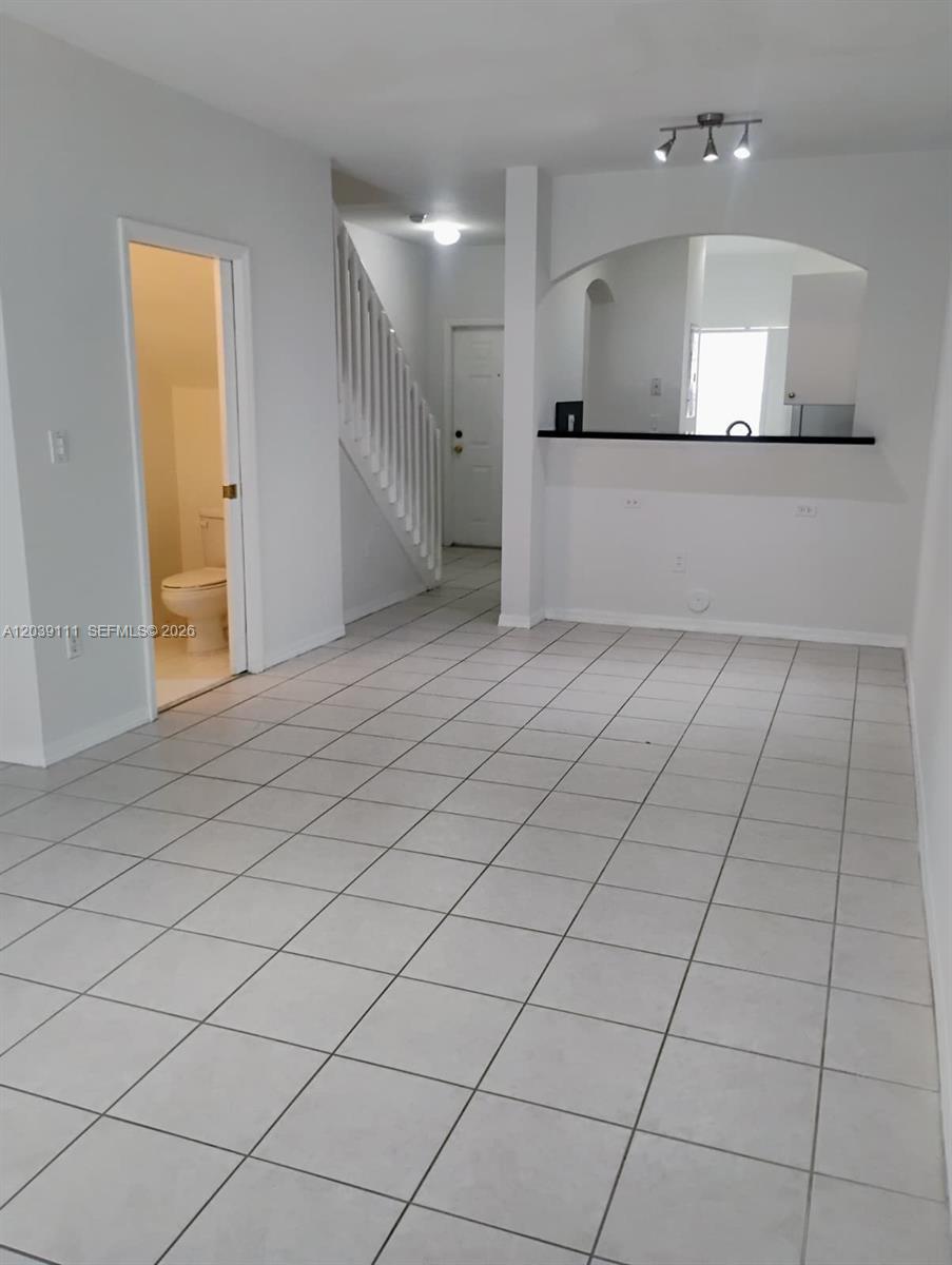 A tiled living area features a staircase, a half bathroom, and a kitchen pass-through window — 5725 NW 114th Path # 107, Doral FL 33178, DORAL, FL