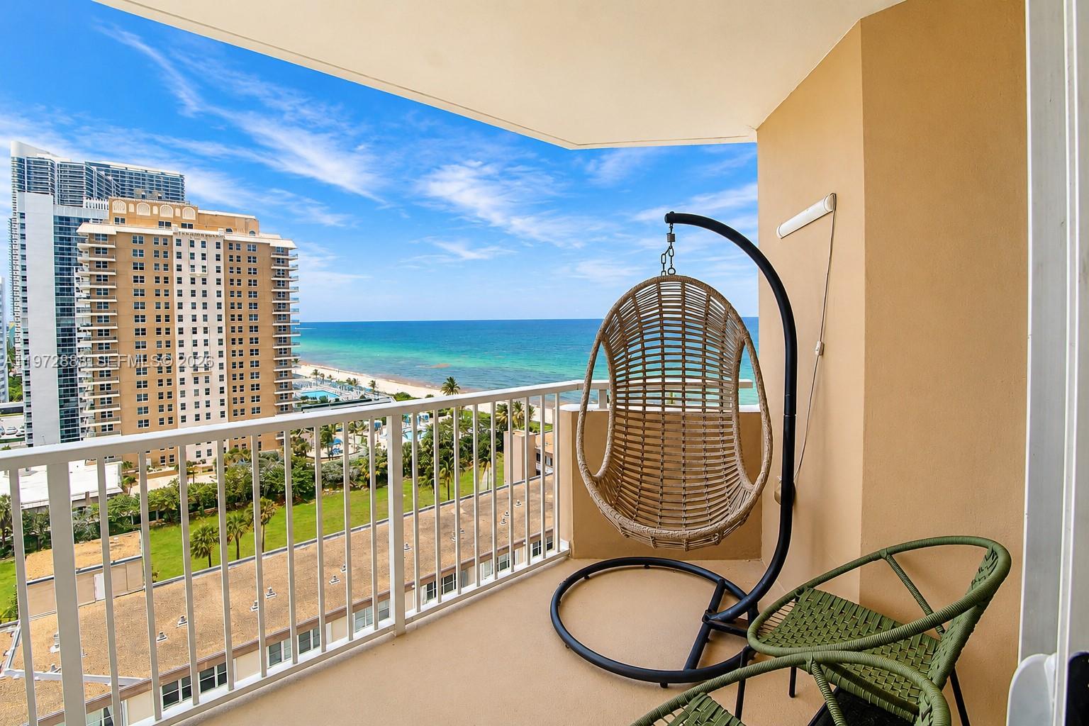 A balcony with a hanging chair, a green chair, and a view of the ocean — 1950 S Ocean Dr # 11D, Hallandale Beach FL 33009, HALLANDALE BEACH, FL