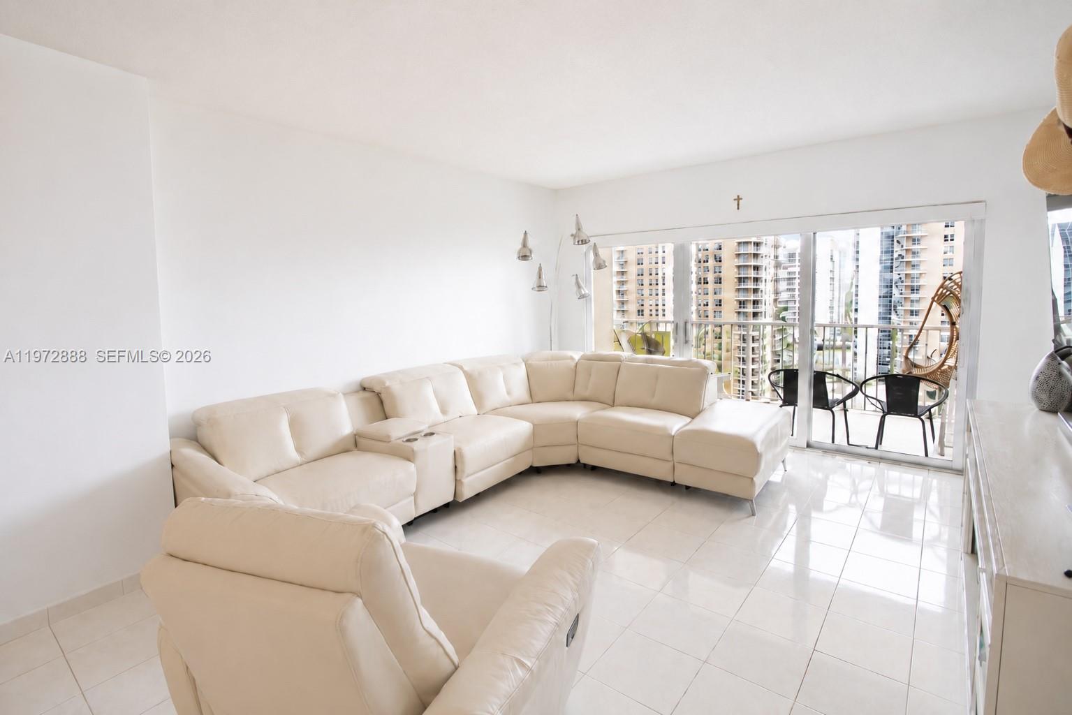 A white living room features a large sectional sofa, a recliner, and a balcony view — 1950 S Ocean Dr # 11D, Hallandale Beach FL 33009, HALLANDALE BEACH, FL
