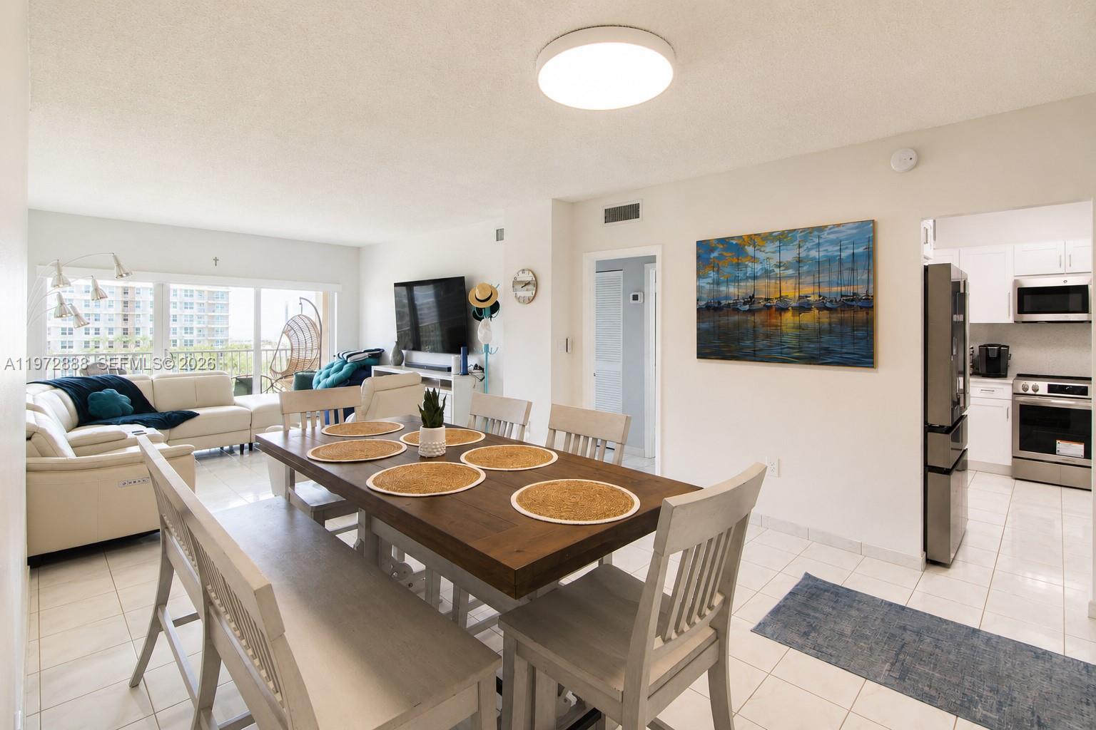 A dining area with a wooden table and chairs sits adjacent to a living room — 1950 S Ocean Dr # 11D, Hallandale Beach FL 33009, HALLANDALE BEACH, FL