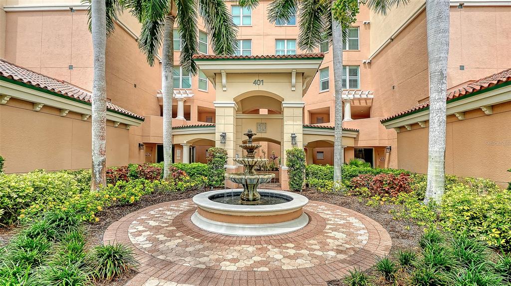 A stone fountain sits in the center of a circular brick courtyard before a building — 401 N POINT ROAD UNIT 504, OSPREY, FL