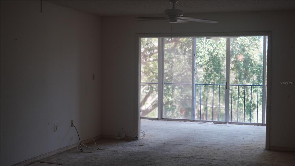 An interior room with beige carpet, a ceiling fan, and sliding glass doors to a balcony — 90 S HIGHLAND AVENUE UNIT 202, TARPON SPRINGS, FL