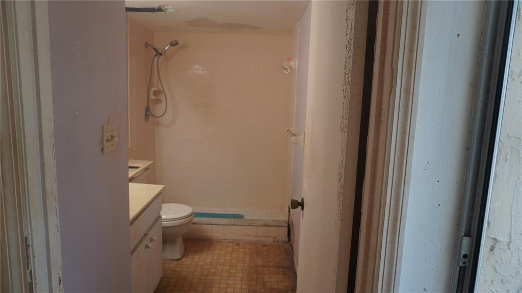 A small bathroom features a vanity, a toilet, and a tiled walk-in shower — 90 S HIGHLAND AVENUE UNIT 202, TARPON SPRINGS, FL