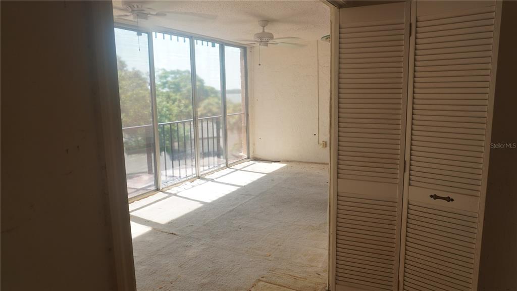 A sunroom with carpeted flooring, ceiling fans, and floor-to-ceiling windows overlooking a body of water — 90 S HIGHLAND AVENUE UNIT 202, TARPON SPRINGS, FL