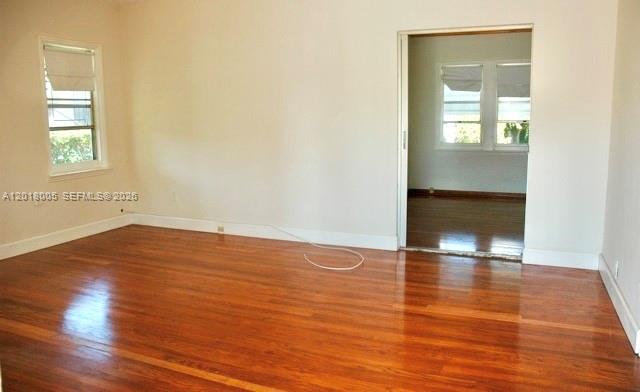 An empty room with hardwood floors and a doorway leading to another sunlit space — MIAMI, FL