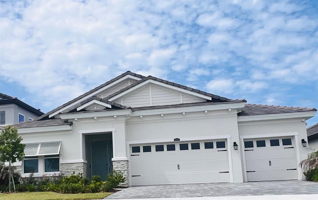 A single-story house with a white stucco exterior, stone accents, and a three-car garage — 9632 SURREY ROSE DRIVE, SAN ANTONIO, FL