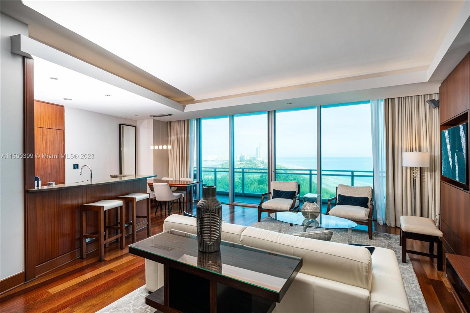 A modern living room features wood floors, a kitchen island, and floor-to-ceiling windows with ocean views — 10295 Collins Ave # 1217, Bal Harbour FL 33154, BAL HARBOUR, FL