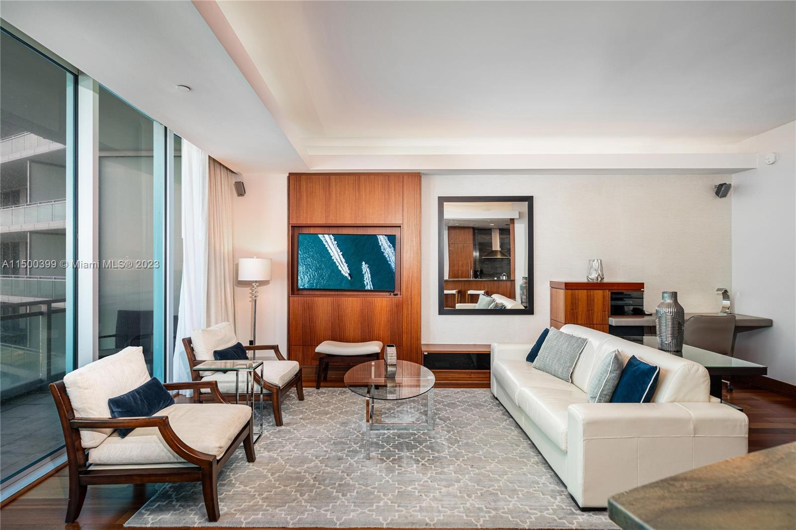 A modern living room features a white sofa, two armchairs, and a wood-paneled television wall — 10295 Collins Ave # 1217, Bal Harbour FL 33154, BAL HARBOUR, FL