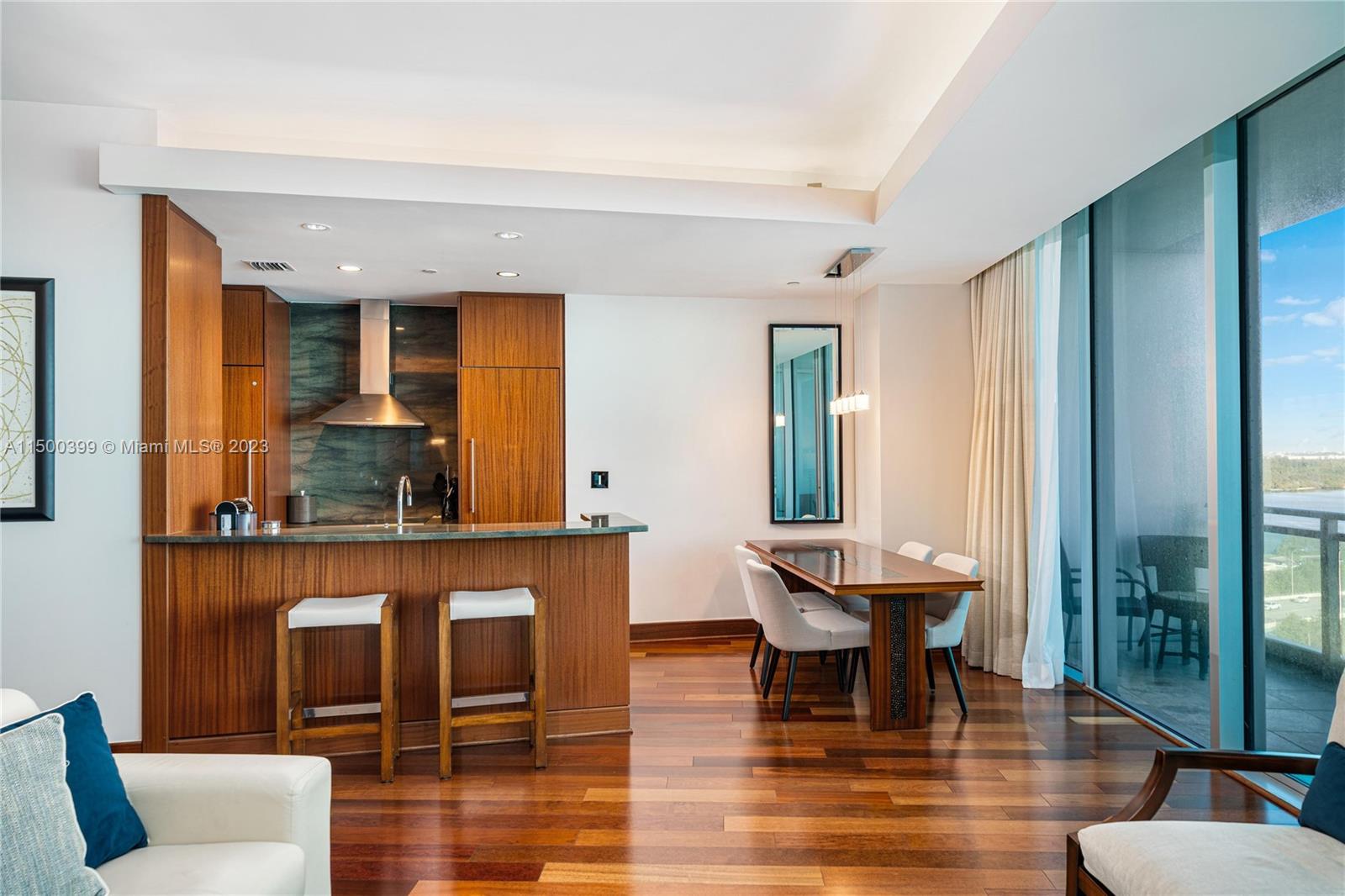A modern kitchen and dining area feature wood cabinetry, hardwood floors, and floor-to-ceiling windows — 10295 Collins Ave # 1217, Bal Harbour FL 33154, BAL HARBOUR, FL
