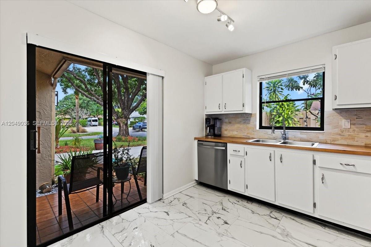 A kitchen features white cabinets, a wood countertop, and a sliding glass door to a patio — 901 NW 26th Ave, Delray Beach FL 33445, DELRAY BEACH, FL