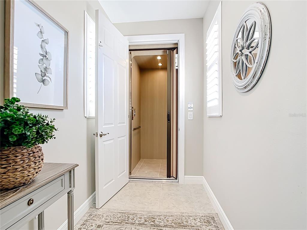 A residential elevator is positioned at the end of a brightly lit hallway — 198 BELLA VISTA TERRACE UNIT C, NORTH VENICE, FL