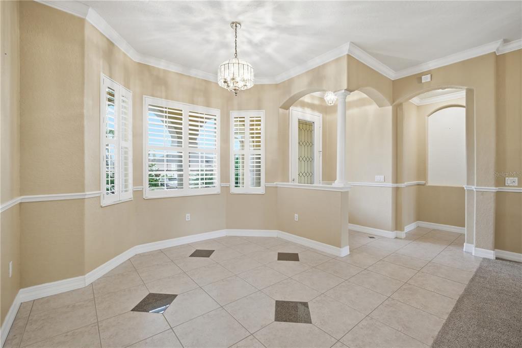 An empty dining room features tan walls, tile flooring with dark accents, and plantation shutters — 718 BUNKER VIEW DRIVE, APOLLO BEACH, FL