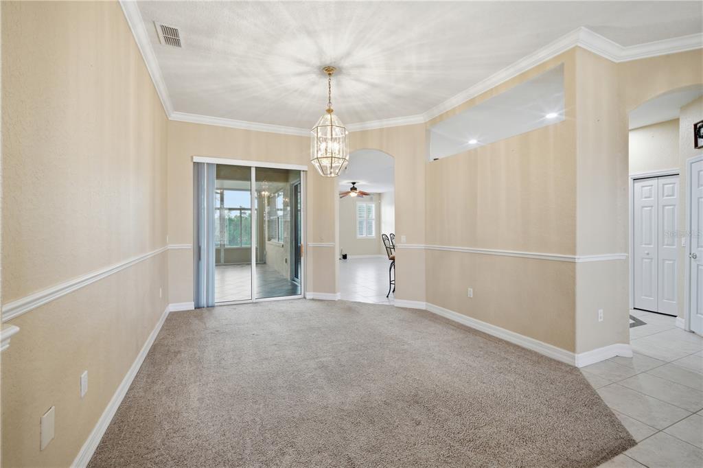 A dining room with beige walls, carpeted flooring, a chandelier, and a sliding glass door — 718 BUNKER VIEW DRIVE, APOLLO BEACH, FL