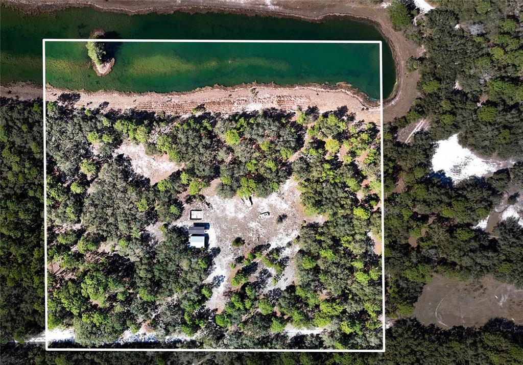 An aerial view shows a house situated on a wooded lot next to a pond — 251 AMBER TRAIL, PALM COAST, FL