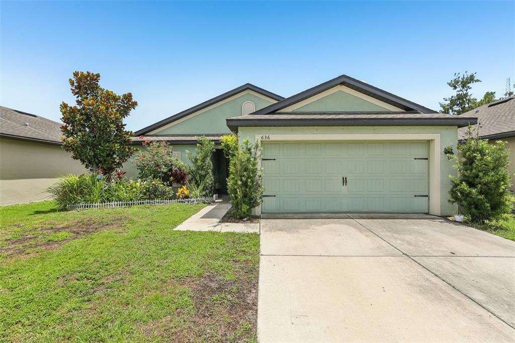 A single-story house with a green exterior, a two-car garage, and a front yard — 636 CHATHAM WALK DRIVE, RUSKIN, FL