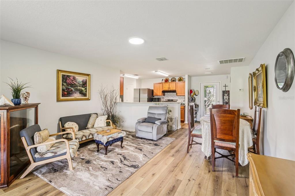 A living room and dining area feature wood-look flooring, a patterned rug, and open kitchen — 636 CHATHAM WALK DRIVE, RUSKIN, FL