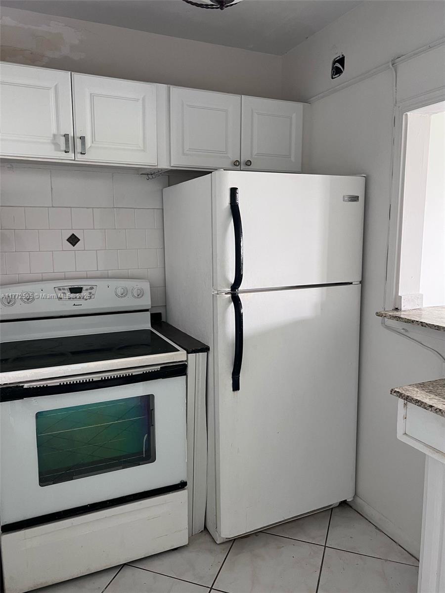 A white kitchen features a stove, a refrigerator, white cabinets, and tiled flooring — 90 Fanshaw C # 90, Boca Raton FL 33434, BOCA RATON, FL