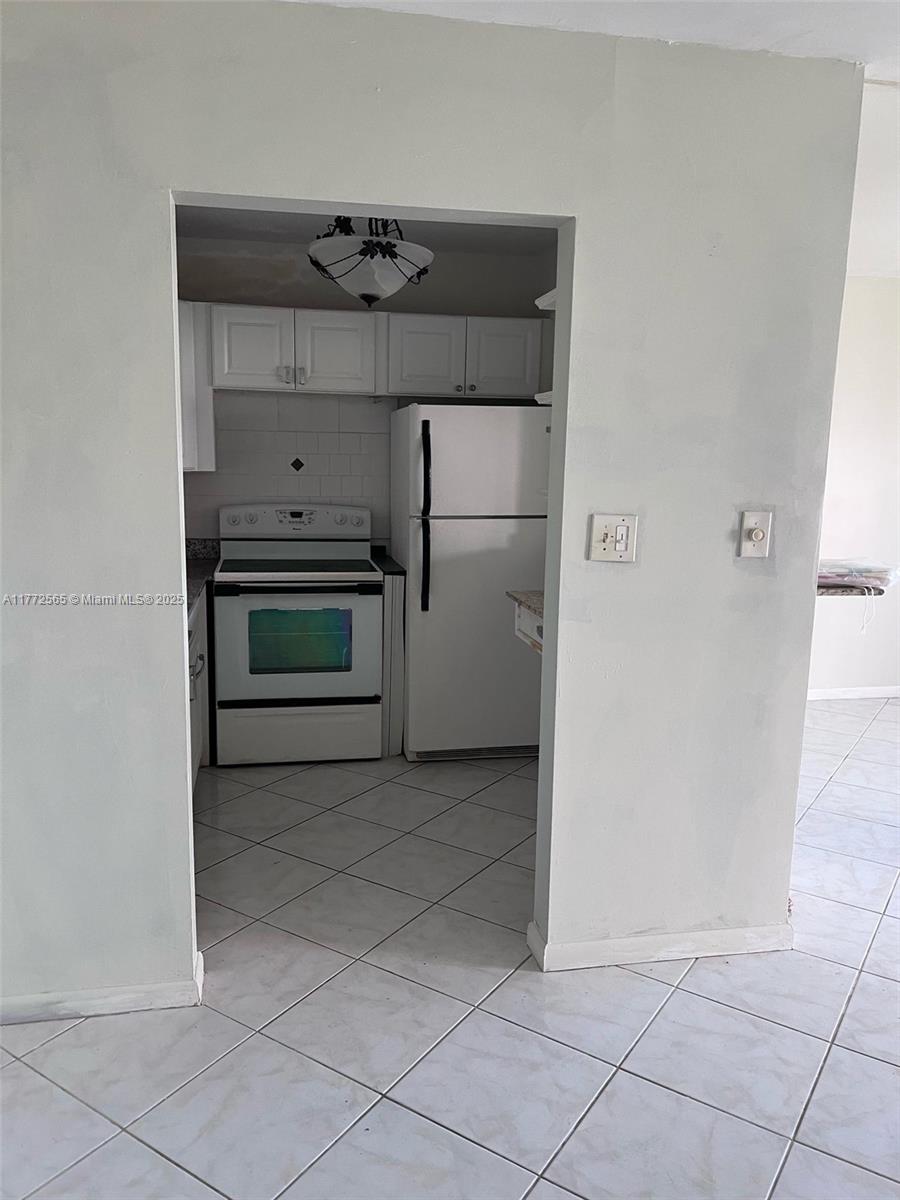 A kitchen with white cabinets, a white stove, and a white refrigerator features tiled floors — 90 Fanshaw C # 90, Boca Raton FL 33434, BOCA RATON, FL