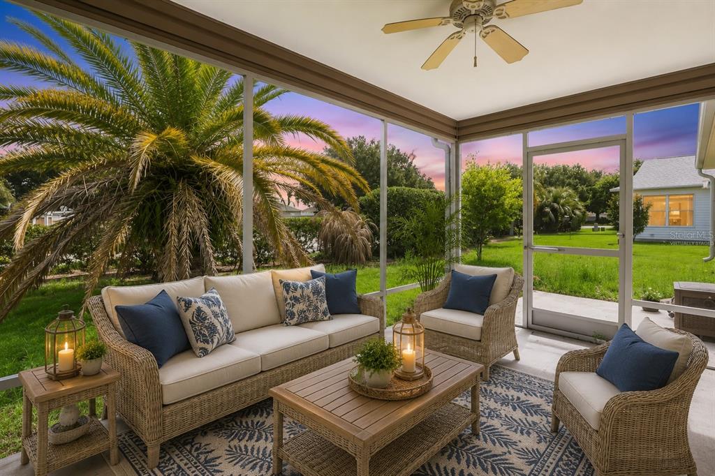 A screened-in patio features wicker furniture, a ceiling fan, and views of a grassy yard — 1575 HOLLYBERRY PLACE, THE VILLAGES, FL