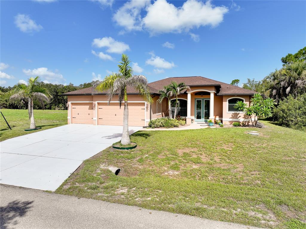 A single-story house with a two-car garage, palm trees, and a paved driveway — 545 PEMBROKE DRIVE, PORT CHARLOTTE, FL