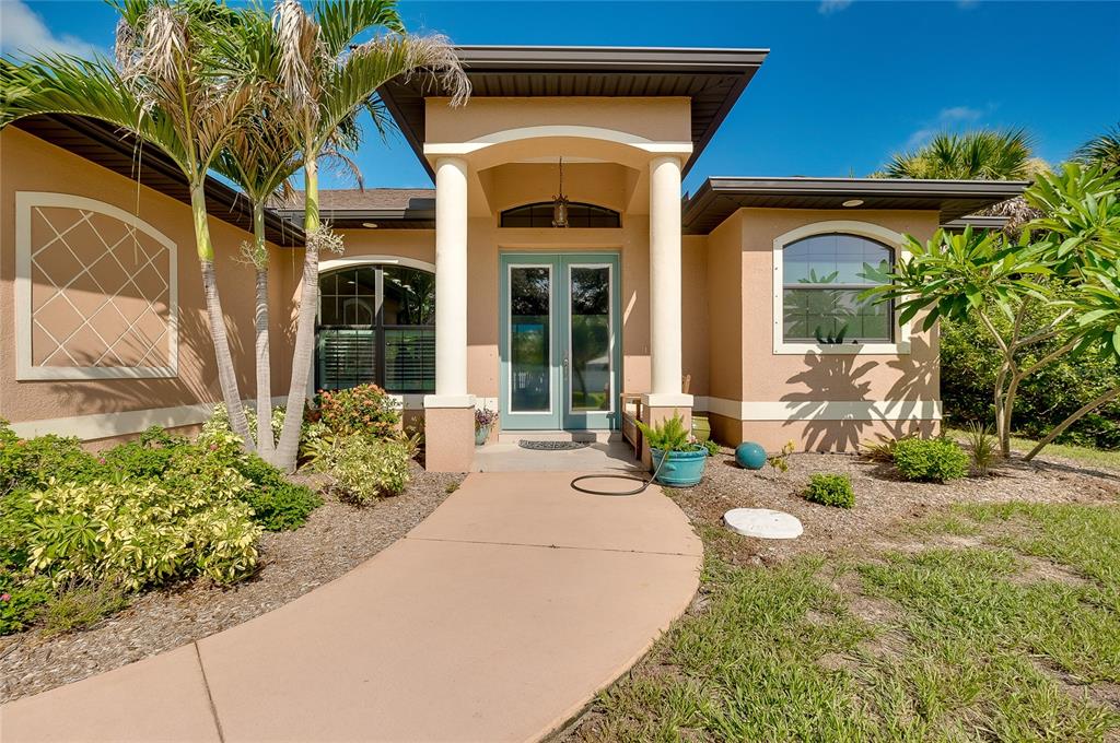 A tan house exterior features a covered entryway with white columns and double glass doors — 545 PEMBROKE DRIVE, PORT CHARLOTTE, FL