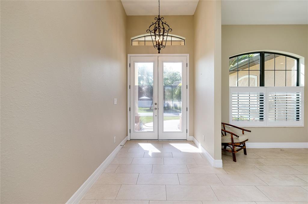 An entryway features light tile flooring, a wrought iron chandelier, and double glass front doors — 545 PEMBROKE DRIVE, PORT CHARLOTTE, FL