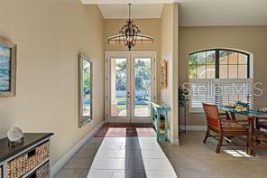 A bright entryway features tile flooring, a chandelier, double glass doors, and a dining area — 545 PEMBROKE DRIVE, PORT CHARLOTTE, FL