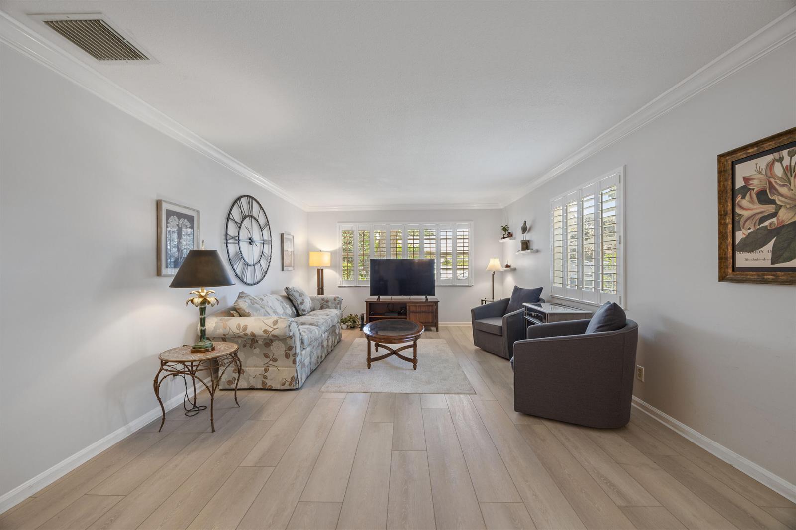 A living room features light wood flooring, a floral sofa, two armchairs, and plantation shutters — 10116 46th Avenue S # 488, Boynton Beach FL 33436, BOYNTON BEACH, FL