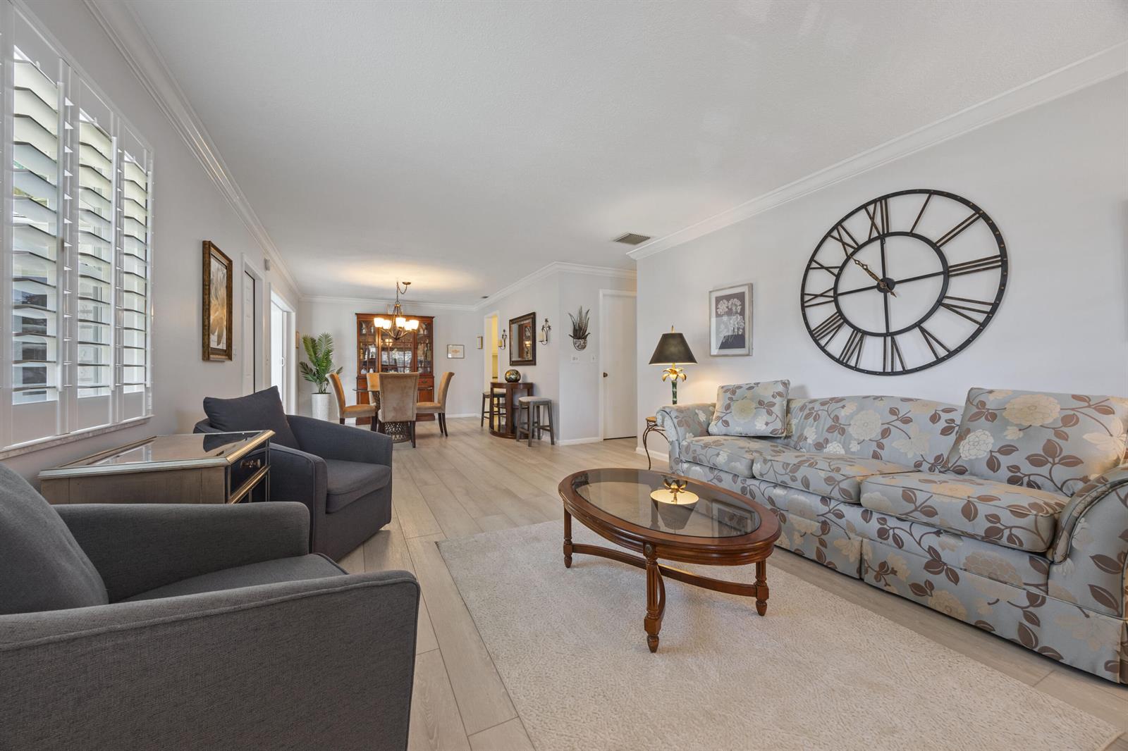A living room features a floral sofa, two gray armchairs, and a large wall clock — 10116 46th Avenue S # 488, Boynton Beach FL 33436, BOYNTON BEACH, FL