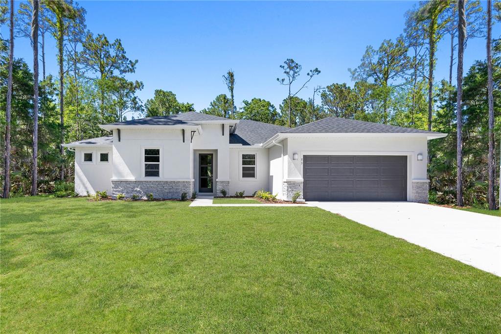 A white single-story house features a gray garage door, stone accents, and a front lawn — 3518 NW 44TH PLACE, CAPE CORAL, FL