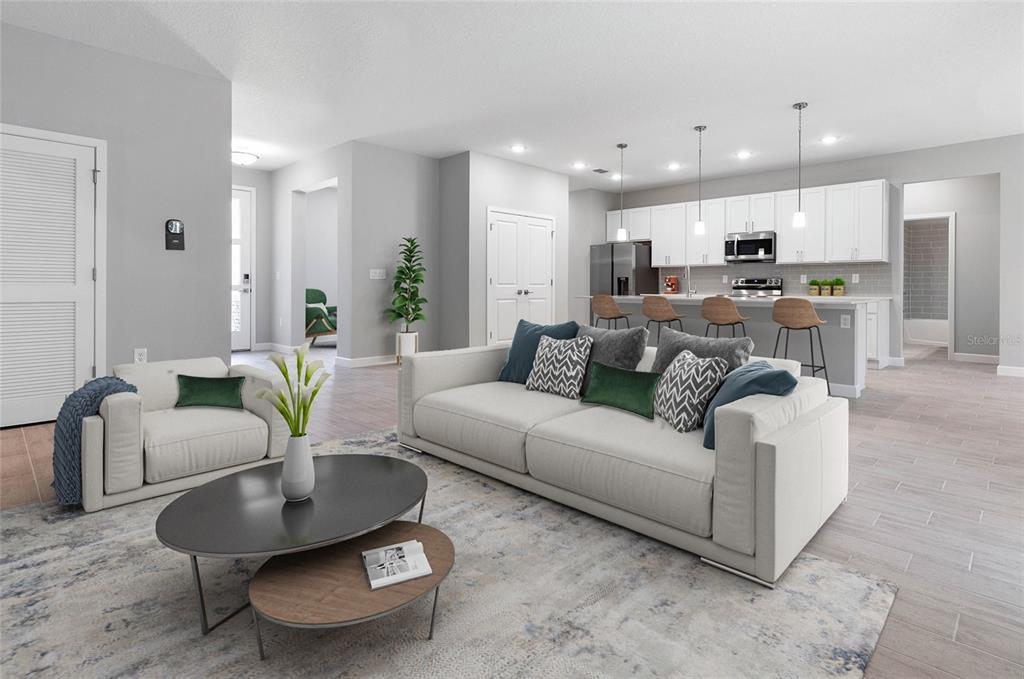 A modern open-concept living room features a white sofa, coffee tables, and a kitchen island — 3518 NW 44TH PLACE, CAPE CORAL, FL