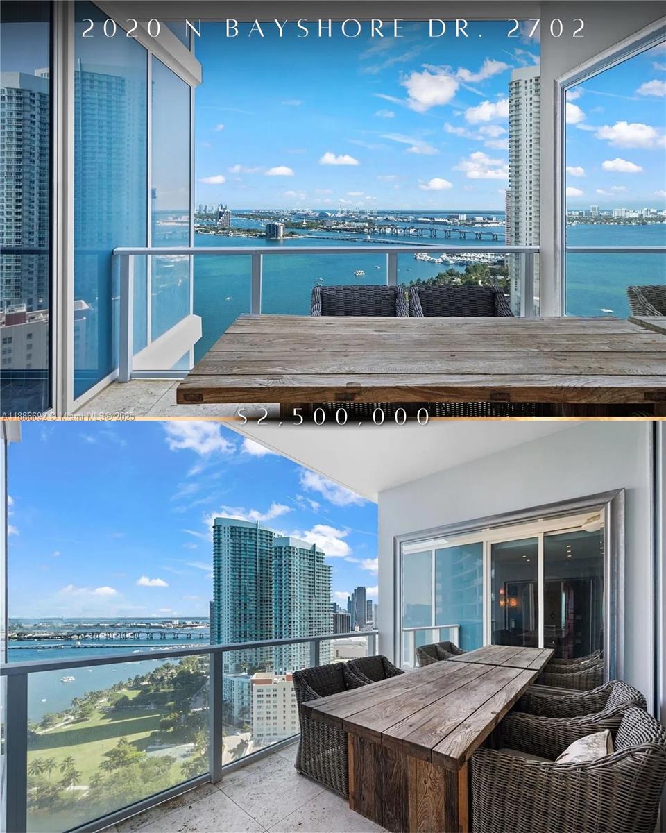 A balcony with a wooden dining table overlooks a bay and city skyline — 2020 N Bayshore Dr # 2702, Miami FL 33137, MIAMI, FL